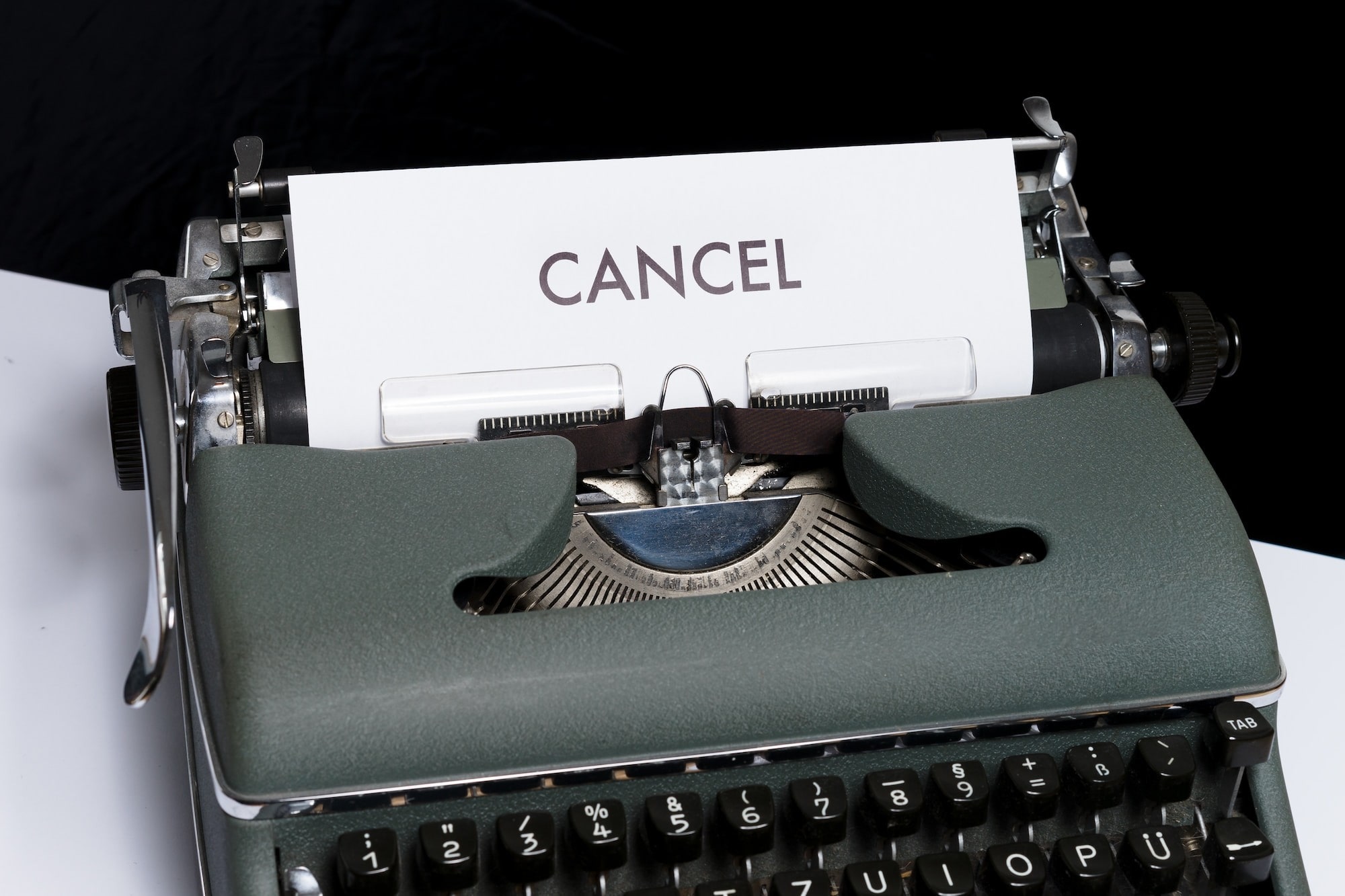 Text saying Cancel at Any Time, with an image of a typewriter and a  piece of paper with the word Cancel typed on it