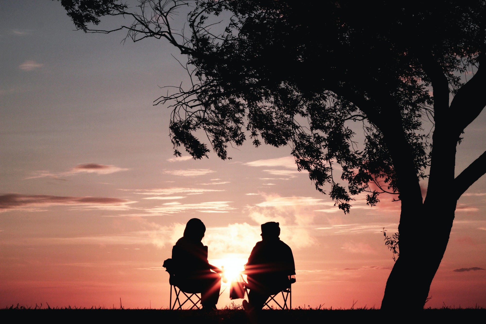 Two people sitting outside watching the sunset together