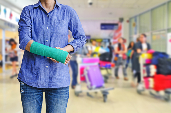 Woman standing while holding her arm which is wrapped in a cast
